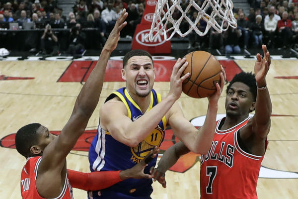 Klay Thompson de los Warriors (cent.) anota una canasta ante el acecho de Kris Dunn (32) y Justin Holiday de los Bulls. Foto:AP