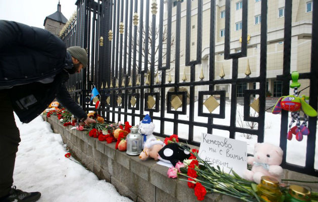 Un hombre observa juguetes mientras recuerda que murieron 41 niños en el siniestro siberiano. Foto: EFE