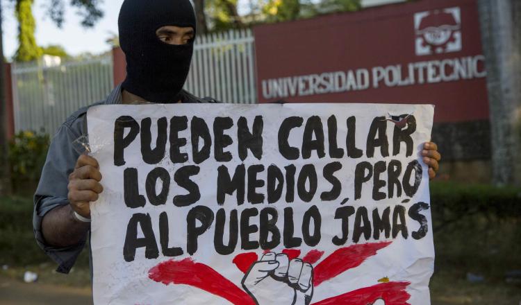 Un joven con una cartel protesta frente a las instalaciones de la universidad politécnica de Nicaragua. EFE