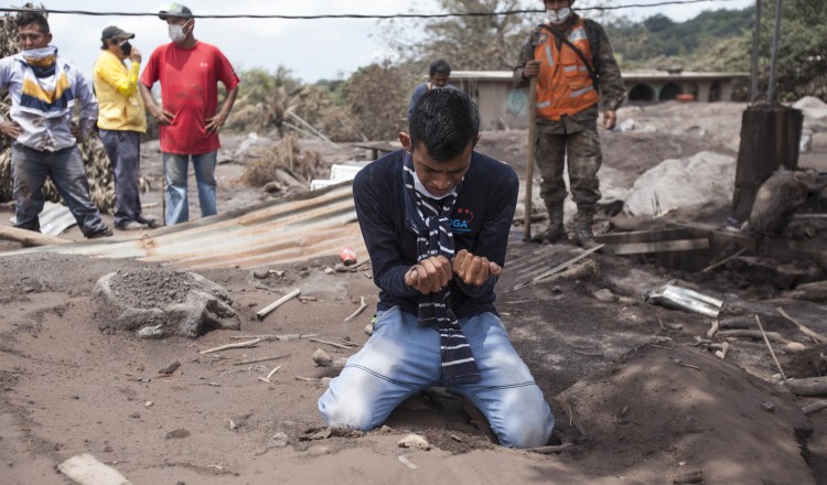 Bryan Rivera llora en medio del lugar que era su casa y donde perdió a sus familiares debido a la erupción del volcán. AP