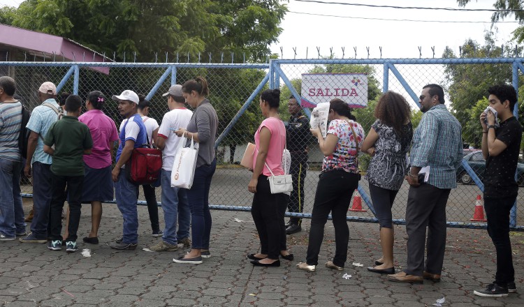 Personas hacen fila para solicitar pasaporte en las oficinas de Migración en Managua. EFE