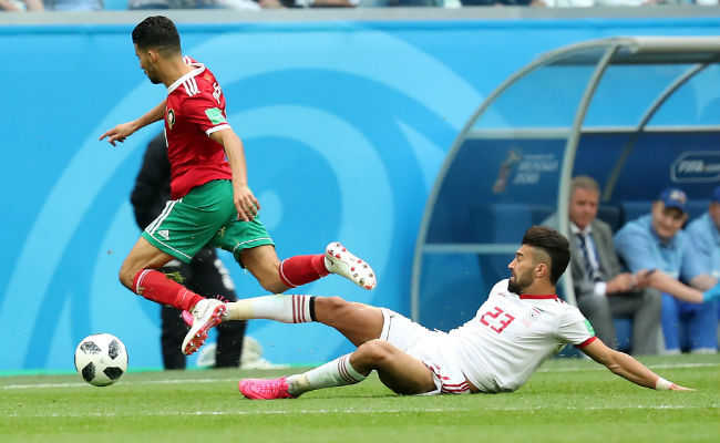Ramin Rezaeian DE IrÁn (Der.) comete una falta ante Mbark Boussoufa de Marruecos. Fot :AP