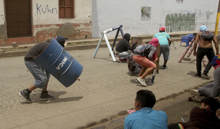 Los manifestantes se defienden con piedras y palos. AP