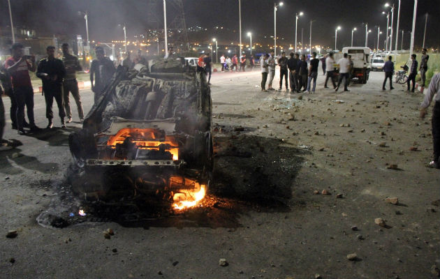 Varios curiosos observan como un coche arde en el lugar del accidente. Foto: EFE 