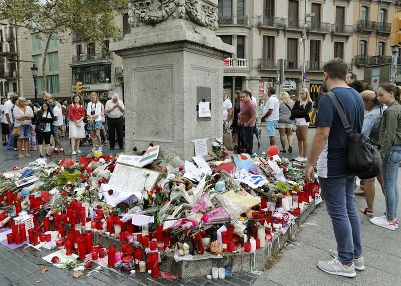 Barceloneses y turistas hacen un alto en el Memorial con flores a las víctimas de atentado terrorista, situado al comienzo de las Ramblas de Barcelona. Foto EFE