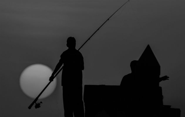 Vista de las siluetas de unos pescadores durante una puesta de sol en Kuwait. Foto: EFE.