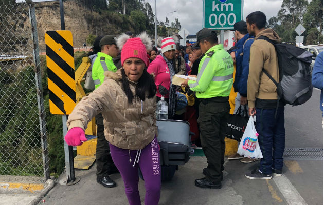 Policías ecuatorianos controlan una fila de emigrantes venezolanos en Rumichaca. Foto: EFE. 