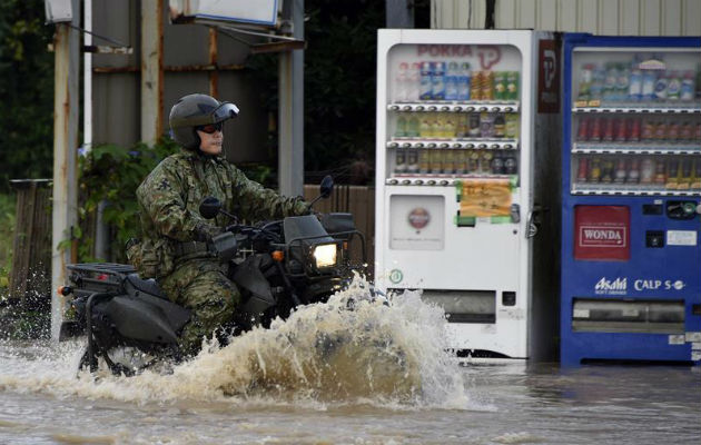 Un miembro de la Fuerza japonesa de Autodefensa pasa en una moto por una calle inundada en Japón. Foto: EFE