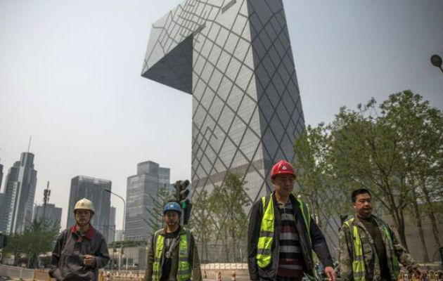 Trabajadores caminan por el distrito financiero de Pekín, en China, cuya economía siguió desacelerándose en el tercer trimestre. EFE