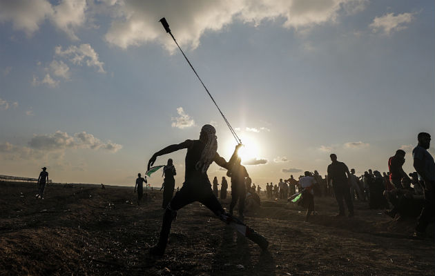 Un  israelí observa su vehículo impactado por misiles tirados desde la Franja de Gaza. Foto: AP. 