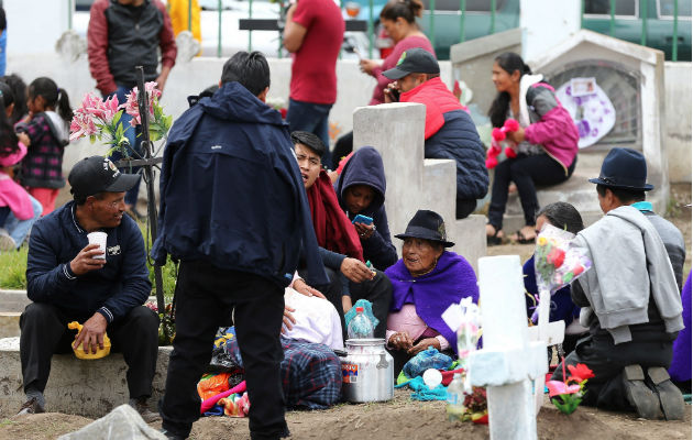 Indígenas comen sobre las tumbas en la celebración del Día de Muertos en Calpi, provincia de Chimborazo, Ecuador. Foto.EFE.