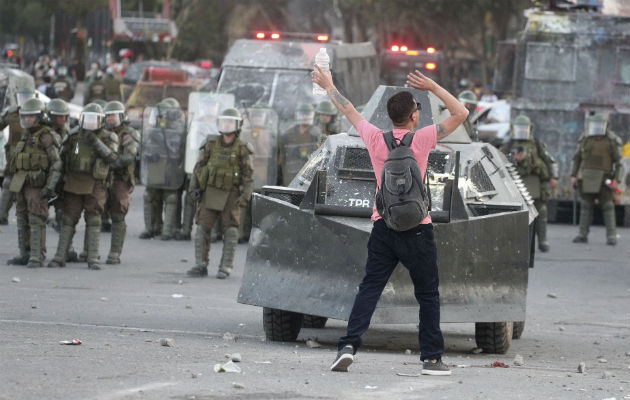 Manifestante chileno frente a policías antidisturbios en Santiago. Foto: AP.