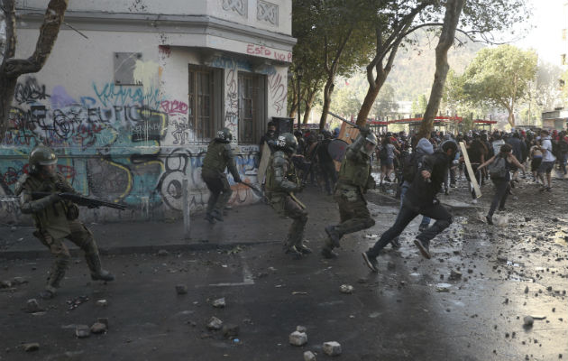 Manifestante chileno frente a policías antidisturbios en Santiago. Foto: AP.