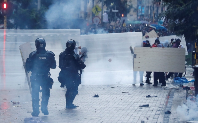 Manifestantes se cubren de los miembros de la Policía antidisturbios en la Plaza de Bolívar. FOTO/EFE