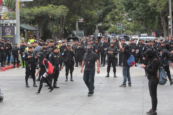 Jóvenes encapuchados son rodeados por miembros de la policía durante una protesta contra la investidura de Alejandro Giammattei FOTO/EFE