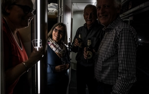 Pasajeros conviven en el pasillo del vagón dormitorio disfrutando bebidas en el Nightjet. Foto / Maxim Babenko para The New York Times.