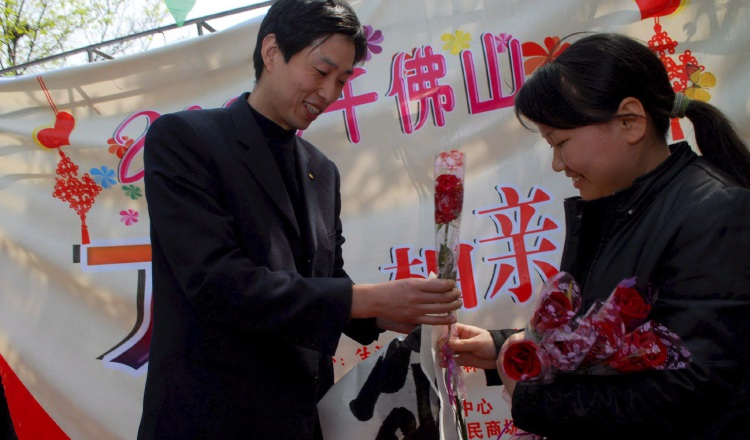Una mujer que busca pareja entrega una rosa a un hombre en una fiesta en el parque Qianfoshan, en Jinan, provincia de Shandong. EFE/Wu Hong