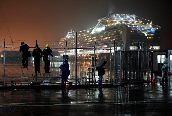 Un grupo de periodistas espera la salida de los buses con pasajeros del crucero que serían llevados a centros hospitalarios. FOTO/AP