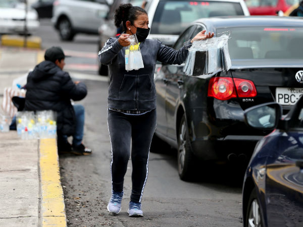 Una mujer con tapabocas vende objetos en las calles de Quito (Ecuador). Foto: EFE.