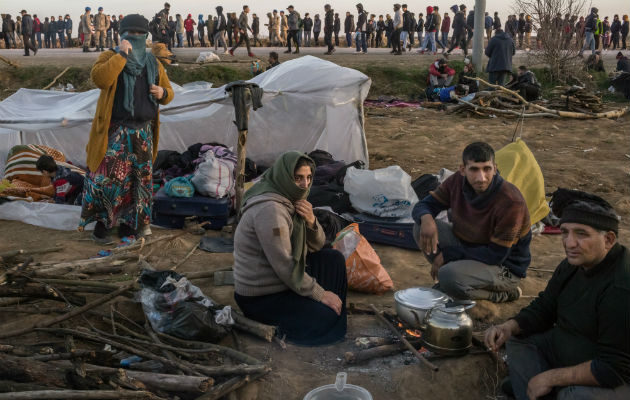 Migrantes descansan mientras cientos más hacen fila para comer en un cruce fronterizo de Turquía con Grecia. Foto / The New York Times.