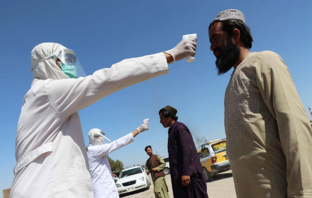 Un trabajador afgano se somete a la toma de temperatura antes de entrar a la ciudad de Kandahar. Fotos: EFE.