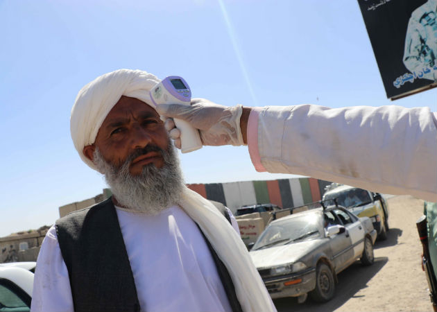Un trabajador afgano se somete a la toma de temperatura antes de entrar a la ciudad de Kandahar. Fotos: EFE.