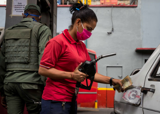 Una mujer en una estación de gasolina carga combustible a un vehículo en Caracas. Fotos: EFE. 