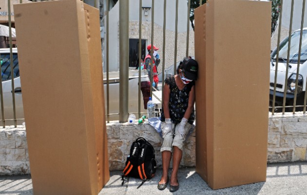 Una mujer llora afuera de un cementerio en Guayaquil junto a cajas de cartón usadas como ataúdes. Foto / Jose Sanchez/Agence France-Presse — Getty Images.