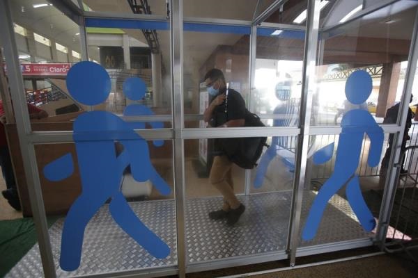 Usuarios de la terminal de transporte de Albrook pasan por una cabina de desinfección instalada en la terminal de autobuses antes de los abordajes. 