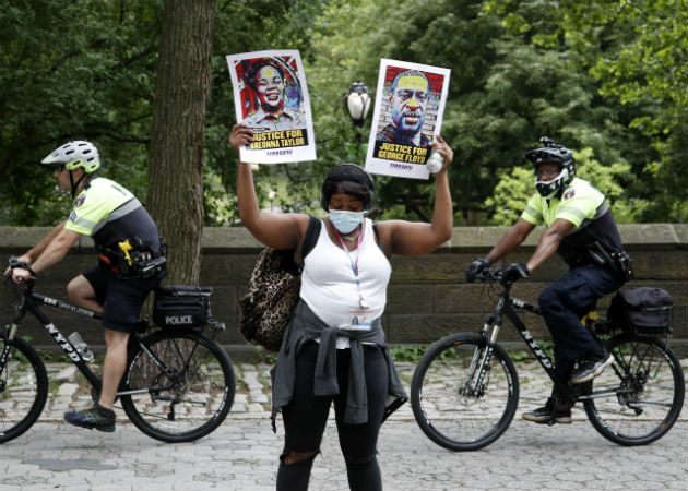 Una manifestante porta retratos de afroamericanos víctimas del racismo. Fotos: EFE.