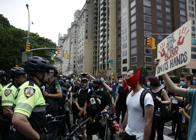 Una manifestante porta retratos de afroamericanos víctimas del racismo. Fotos: EFE.