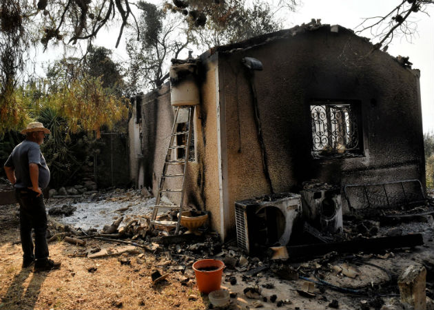 Un hombre observa su vivienda arrasada por el incendio forestal. Fotos: EFE.