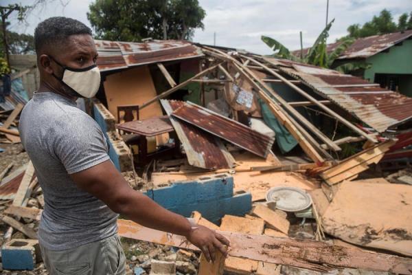 Un hombre intenta reparar su vivienda dañada por el paso del huracán Isaías. FOTO/EFE