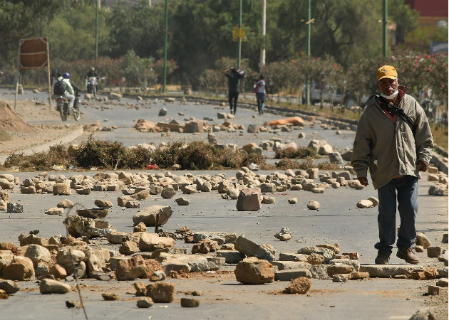 Un hombre cruza un bloqueo de una carretera durante las protestas en Cochabamba. Fotos: EFE.