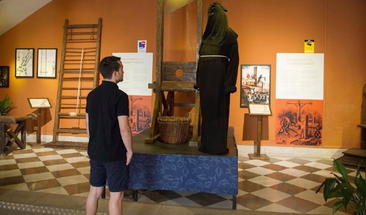 Un hombre observa una guillotina que forma parte de la exposición 