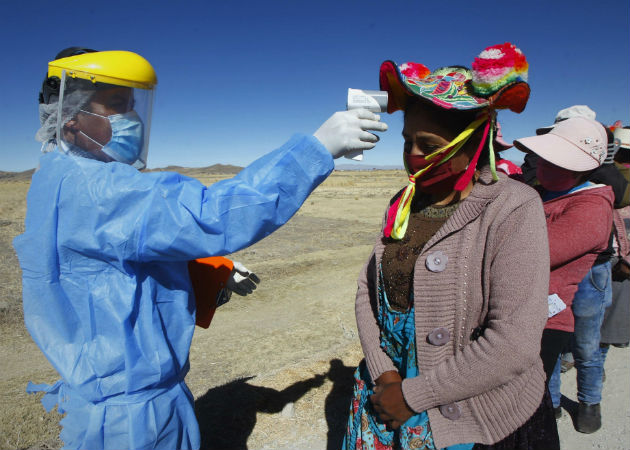 Un hombre toma la temperatura a mujeres Quechuas en la localidad de Coata, a unos cuarenta minutos de la ciudad de Puno (Perú). Fotos:EFE.