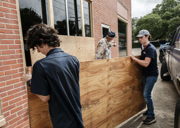 Un padre y su hijo colocan tablones en su local comercial en Louisiana. Fotos: EFE.