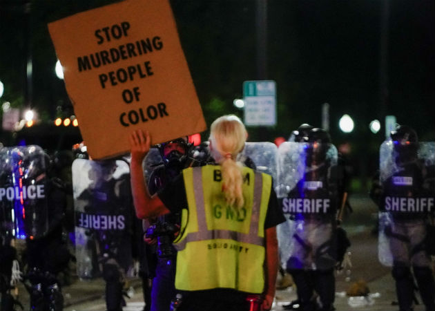 Afroamericano herido por policía sufre parálisis en parte inferior de cuerpo Una manifestante confronta a la Policía en Kenosha (EE.UU.), en la continuación de las protestas por el ataque policial contra Jacob Blake. Fotos. EFE.