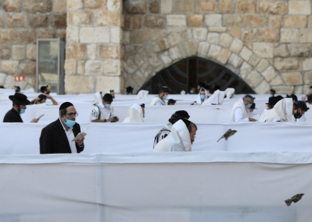 Judíos ortodoxos oran en el muro al oeste de la vieja ciudad de Jerusalén, a dos días de reiniciar el aislamiento total por el coronavirus. EFE.