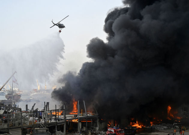 Un mes tras la explosión, un incendio en el puerto estremece de nuevo Beirut Un helicóptero de la armada lanza agua al fuego en el puerto de Beirut (Líbano). Fotos:EFE.