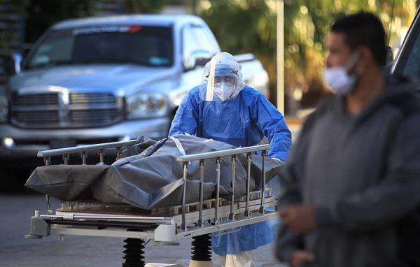 Un paramédico traslada un cuerpo de una persona fallecida por la COVID-19