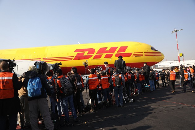 Periodistas observando el desembarque con las primeras vacunas contra la COVID-19, procedentes de Bélgica, al aeropuerto Internacional de La Ciudad de México. Foto: EFE