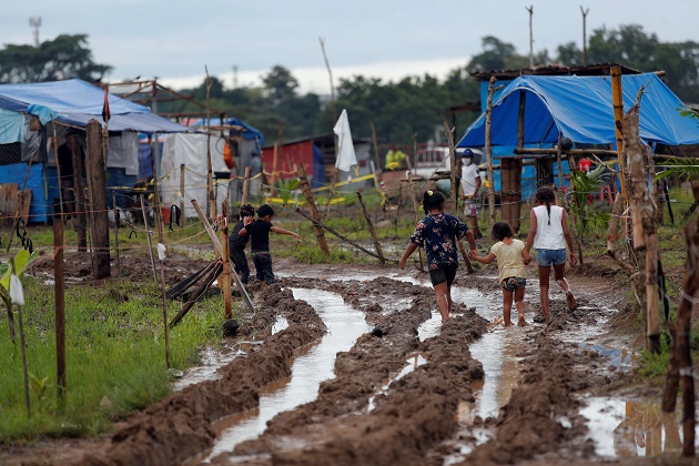 Niños recorren un camino lodoso en el terreno "Victoriano Lorenzo", en el sector de la 24 de Diciembre. Foto: EFE