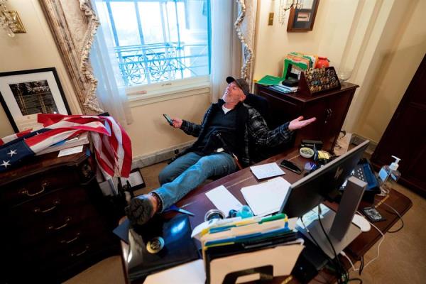Un seguidor de Donald Trump se sienta en el escritorio de la presidenta de la Cámara Baja.