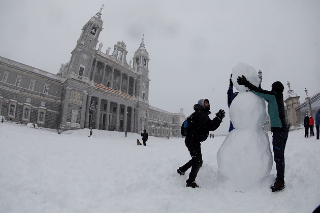 Personas hacen hoy un muñeco de nieve en las inmediaciones de la Catedral de la Almudena , en Madrid. Foto: EFE