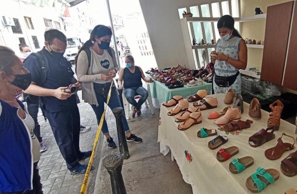 Varias personas observan algunos modelos en un puesto de venta de sandalias hoy, en La Habana