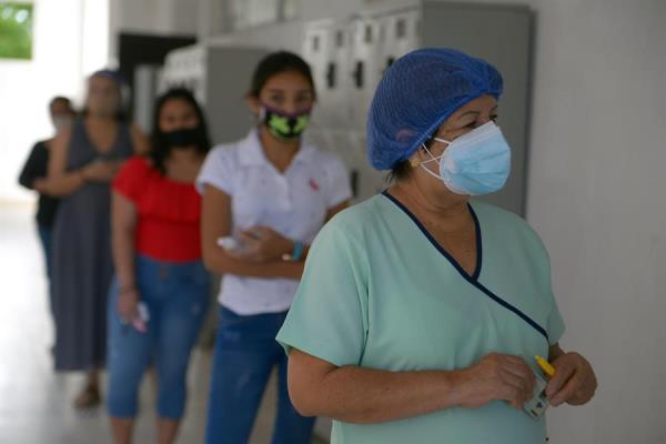 Mujeres esperan en fila para votar hoy, en un centro electoral en Guayaquil
