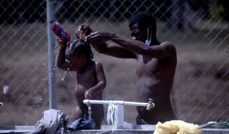 Un padre migrante  baña  a su hijo en el albergue de San Vicente, provincia de Darién. Víctor Arosemena