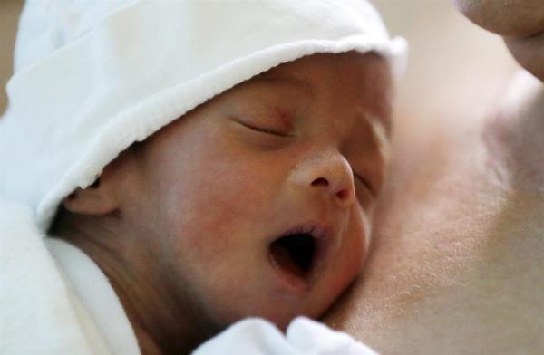 Una mujer sostiene en sus brazos a su recién nacido durante el primer contacto piel con piel. 