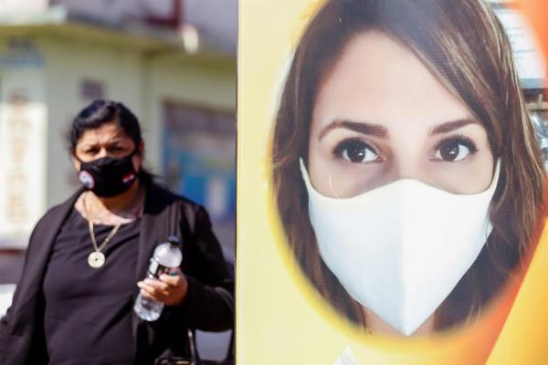 Fotografía que muestra una mujer mientras pasa al lado de un cartel hoy en la zona del mercado 4 de Asunción (Paraguay).